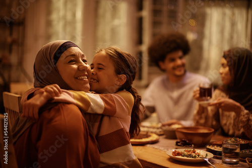 Photography Happy Muslim little girl embracing her grandmother in dining room