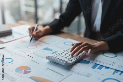 Close-up of a business woman's hands using a calculator to calculate and take notes to audit company accounts, finances, income, balance sheets and budgets.