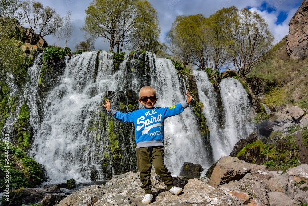 A little boy near the Shaki waterfall, with a height of 18 m. It is located in the Syunik region of Armenia, near the city of Goris. May 5, 2019