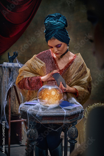 Portrait of magnificent fortune teller woman reading future on magical crystal ball and tarot cards. Concept of vintage style, retro circus, art, fate