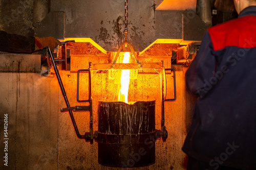 Pouring liquid metal from furnace into vat at metallurgical production. Metal part factory, foundry cast, heavy industry