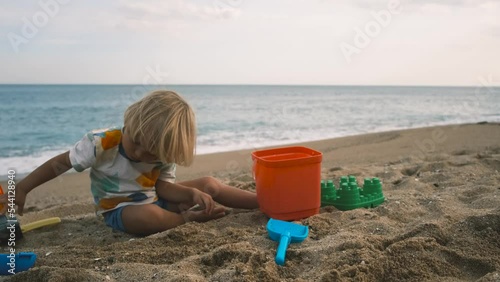 Close-up of a child playing with a shovel and bucket on the sand at the beach