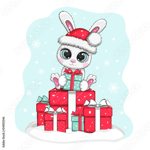 New Year's cute bunny in a red hat with a bumbon holds a gift and sits on the gifts blue photo