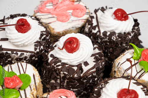 Cakes with chocolate, cherries and cream on a white background.