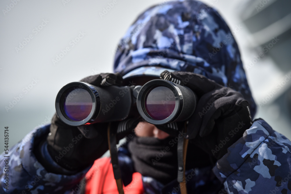 Navy soldier looking through binoculars at the sea Navy soldier looking through binoculars at the sea