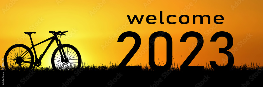 Welcome concept 2023 and happy new year. Cyclist silhouette in the meadow
