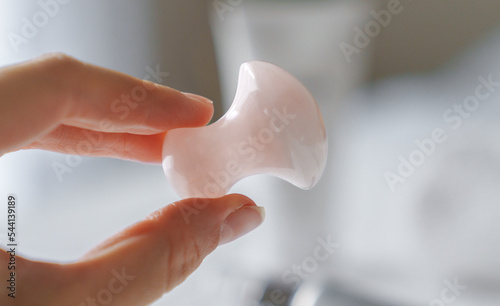 Female hand holding Rose quartz mushroom stone for facial massage