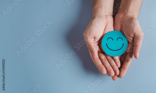 Valokuva Hands holding blue happy smile face, good feedback rating, positive customer rev