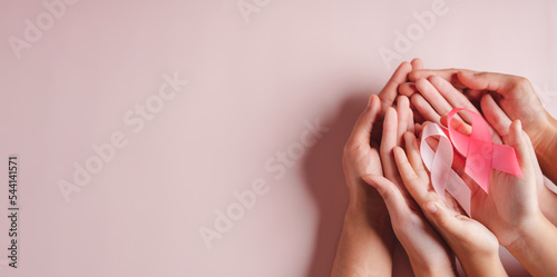 hands of people holding pink ribbons on pink background  Breast cancer awareness  world cancer day  national cancer survivor day in february concept.