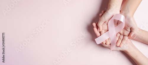 Fotografering hands holding pink ribbons on pink background, Breast cancer awareness, world cancer day, national cancer survivor day in february concept