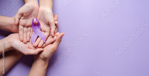hands holding purple ribbons, Alzheimer's disease, Pancreatic cancer, Epilepsy awareness, world cancer day on a purple colored background, World Cancer Day concept photo