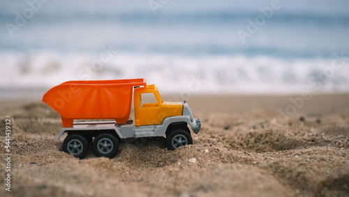 a children's toy car stands on the sand on the beach, sea waves are in the background