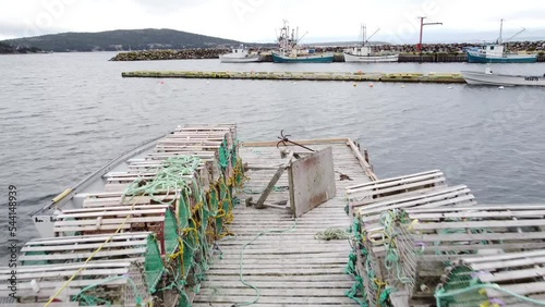 Whiteway Newfoundland Canada, September 27 2022: Tracking through lobster traps on a wooden dock with fishing boats moored at a small harbour.
 photo