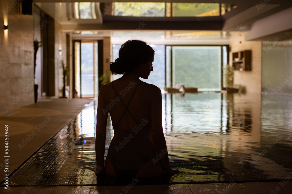 Rear view of young woman relaxing on the poolside Rear view of young woman relaxing on the poolside