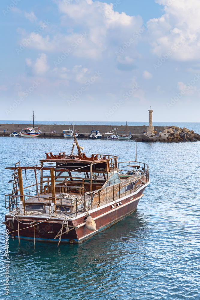a small old fishing boat is parked in the quiet harbor of the Greek town of Hersonissos