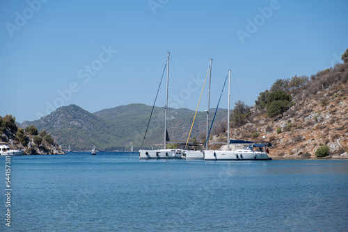 Beautiful bay with sailing boats, yachts in turquoise sea and mountains, luxury holidays or sailing regata sports. © olga_demina