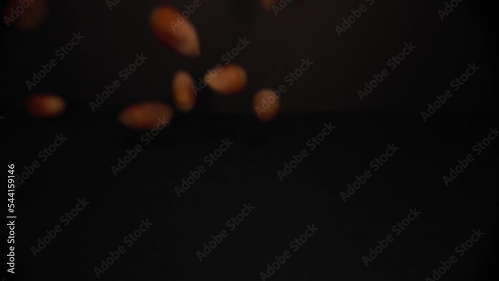 Macro Close Up view of Hazelnuts falling in a black environement in 4K slow motion