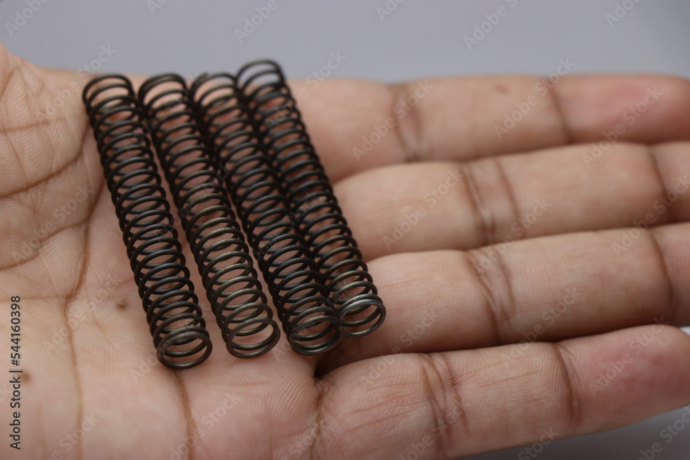 Four steel compression coil springs held in hand. Metal springs as a mechanical part replacement Four steel compression coil springs held in hand. Metal springs as a mechanical part replacement