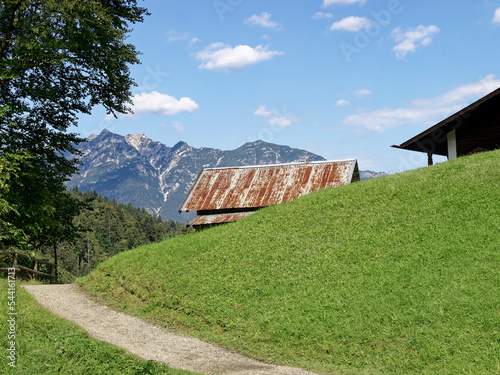 Hiking trail in the Bavarian Alps with a view of the mountains and mountain hut in the middle.
