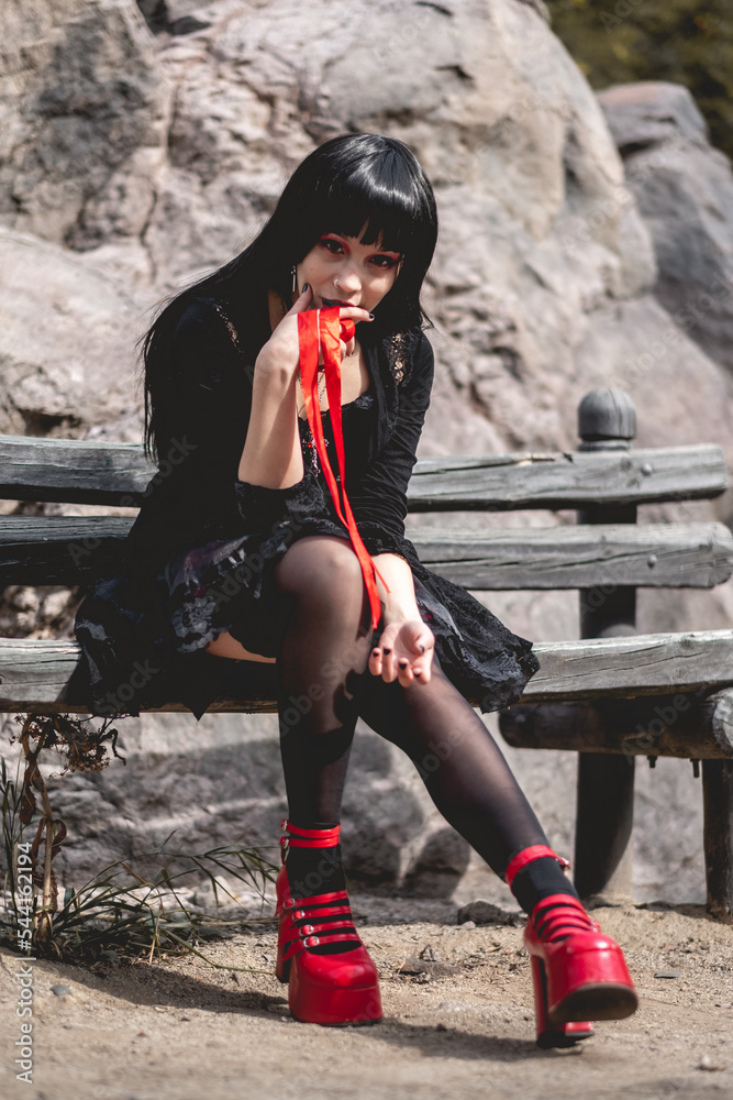 Young, sexy and vampiric hispanic goth girl with black dress and red