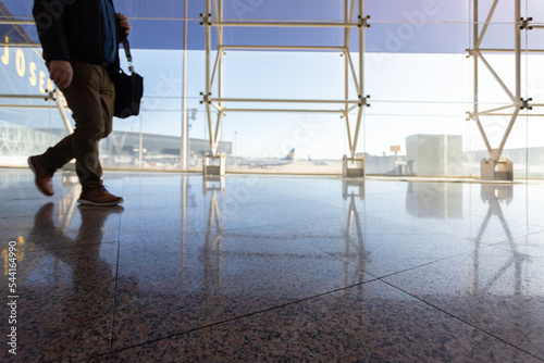 Unrecognizable and out of focus person walking inside an airport photo with copy space.