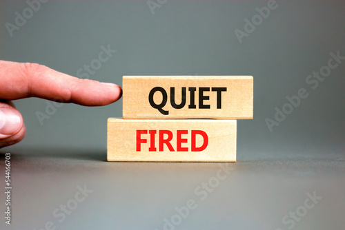 Quiet fired symbol. Concept words Quiet fired on wooden blocks. Beautiful grey table grey background. Businessman hand. Business and quiet fired concept. Copy space.