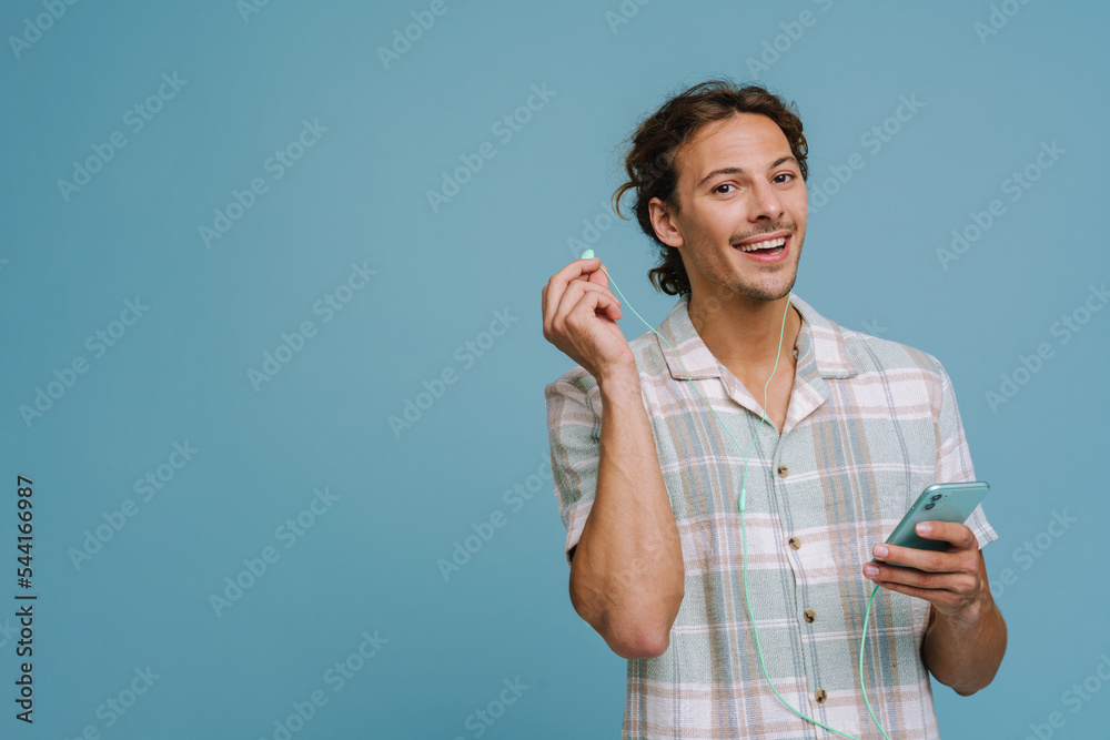 Ginger european man in earphones smiling and using cellphone Ginger european man in earphones smiling and using cellphone
