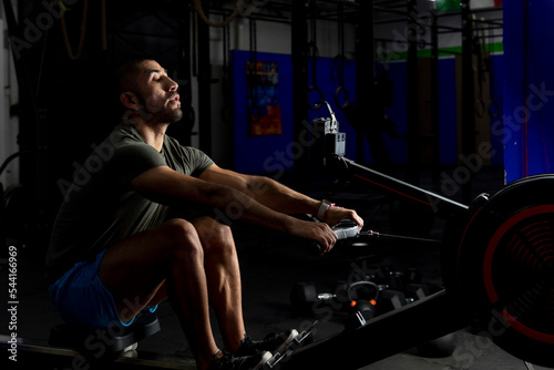 low light shot of an athlete rowing in a gym
