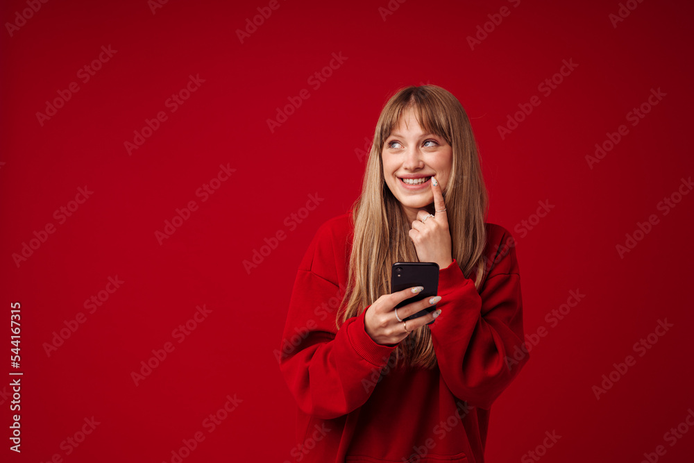 Fototapeta premium Blonde woman wearing hoodie smiling while using cellphone