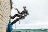 Male worker rope access industrial working at height tank oil wearing harness, helmet safety equipment rope