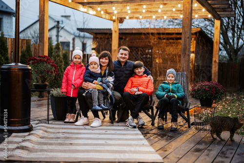 Large family portrait in wooden garden pergola, decor lamp and chairs in autumn.