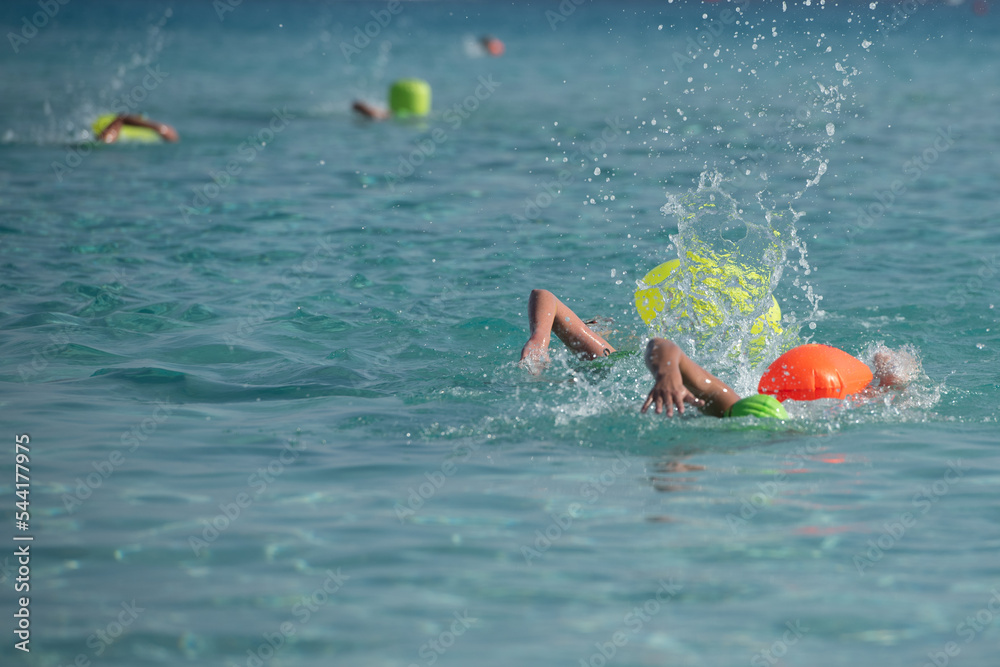 Athletes  swimming free style in the sea  during triathlon competition.  Swimmer in the ocean