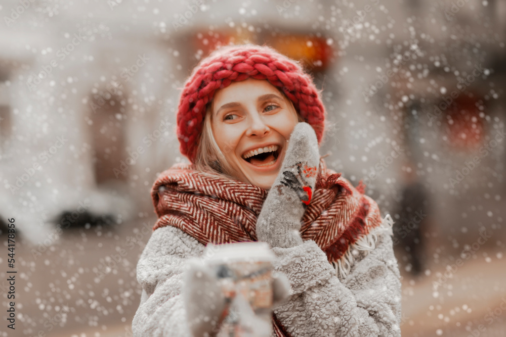 close-up portrait of a happy young girl in a warm hat holding a cup of hot coffee, christmas holiday concept, snowy street close-up portrait of a happy young girl in a warm hat holding a cup of hot coffee, christmas holiday concept, snowy street