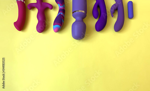 Purple sex toys. Sex shop assortment. Seven vibrators on yellow background