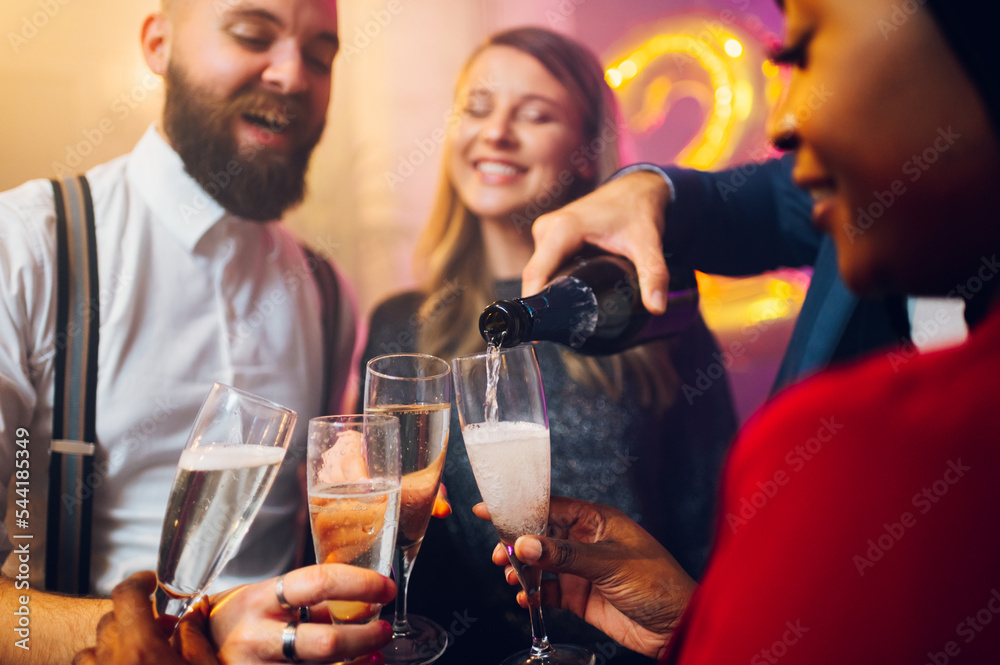 People hands holding flute glasses while pouring champagne People hands holding flute glasses while pouring champagne
