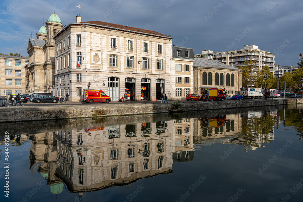 Paris, France - 10 31 2022: Ourcq canal. View of the Canal of the Basin of the villette with reflections of fire station buildings