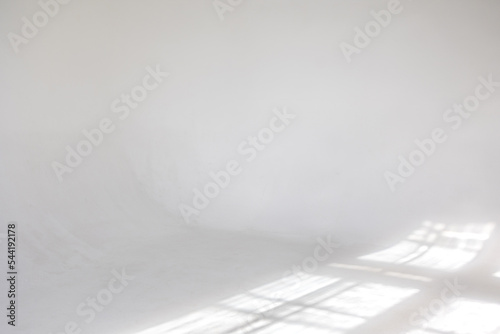 Clear white cyclorama. Light background with sun light and shadows. Plain wall empty photo studio. . High quality photo