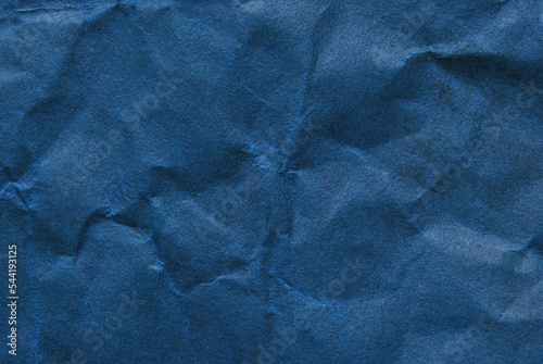 A sheet of wrinkled dark blue color paper texture as background 