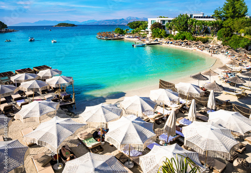 White sandy beach with turkis water and white sunshades in Ksamil Albania  photo