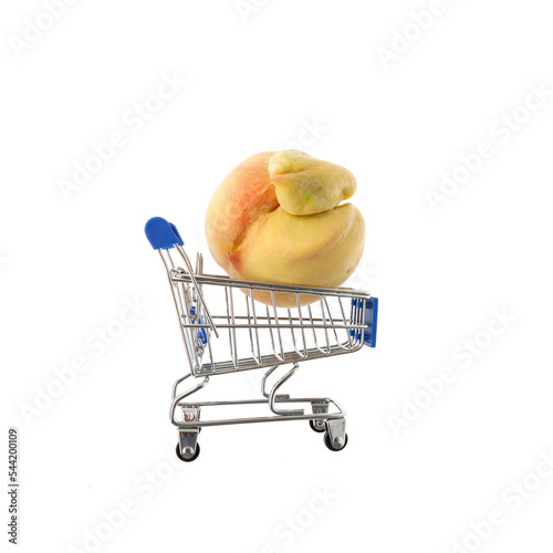 Ugly fruits concept. Deformed peach in trolley (shopping cart) on white background. Design element. Reduce organic food waste. Last trend - Eating imperfect vegetables and fruits photo