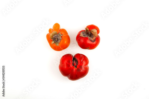 Three deformed Persimmon fruits on white background. Funny Concept - Reduction of organic food waste. Ugly Persimmon. Last trend - Eating imperfect vegetables and fruits photo