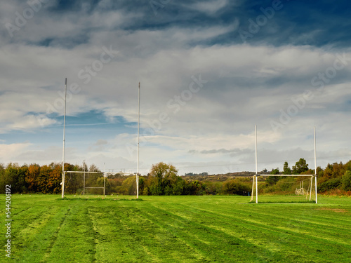 Training pitch for Irish National sport camogie, hurling, rugby and Gaelic football with tall goal posts and freshly cut grass. Nobody. Cloudy sky. Popular activity.