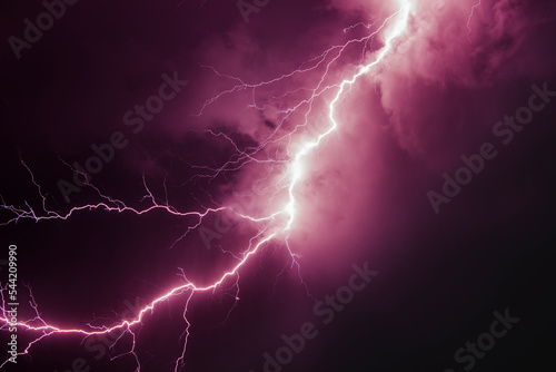 a powerful discharge of purple linear lightning against a dark sky at night