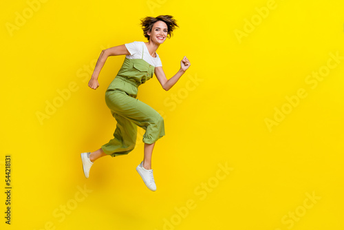 Side profile photo of attractive active girl wear khaki overalls hurry running shopping center low prices summer isolated on yellow color background