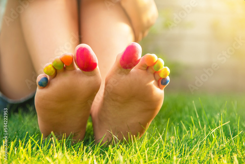 Teenage girl with painted toes sitting on green grass outdoors, closeup © New Africa