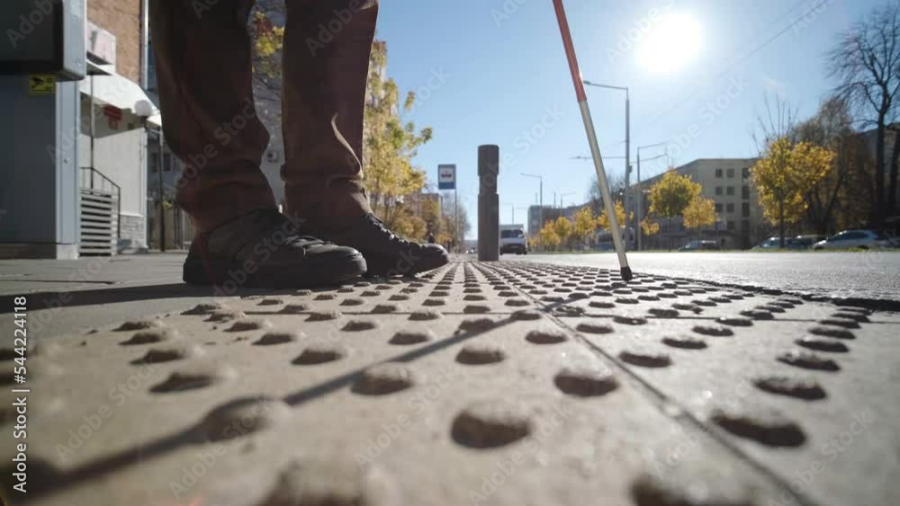 Lone blind man detecting tactile tiles, walking to pedestrian crossing safe road
