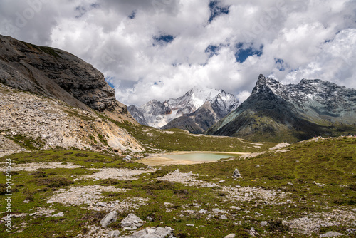 Snow mountains, emerald green seasonal glacier lake under the dense clouds, Daocheng Yading, Sichuan, China, copy space for text, wallpaper