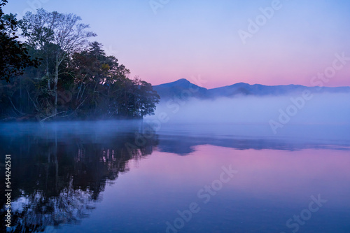 湖面に朝靄の漂う早朝の湖。日本の北海道の屈斜路湖。