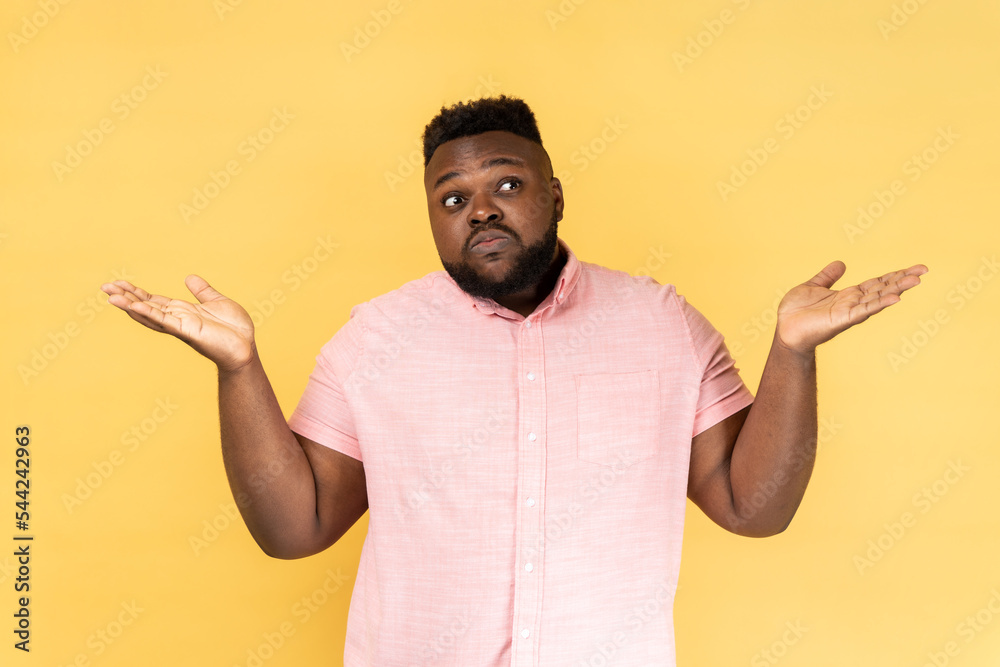 I dont know. Portrait of confused man wearing pink shirt shrugging shoulders as doesn't know answer, can`t make decision, being uncertain, not sure. Indoor studio shot isolated on yellow background. I dont know. Portrait of confused man wearing pink shirt shrugging shoulders as doesn't know answer, can`t make decision, being uncertain, not sure. Indoor studio shot isolated on yellow background.