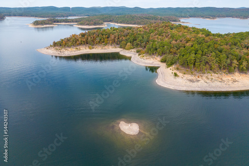 Aerial view of landscape of water of Broken Bow lake and islands with forest on the bank, Oklahoma, USA. Autumn scenery of coastal line.